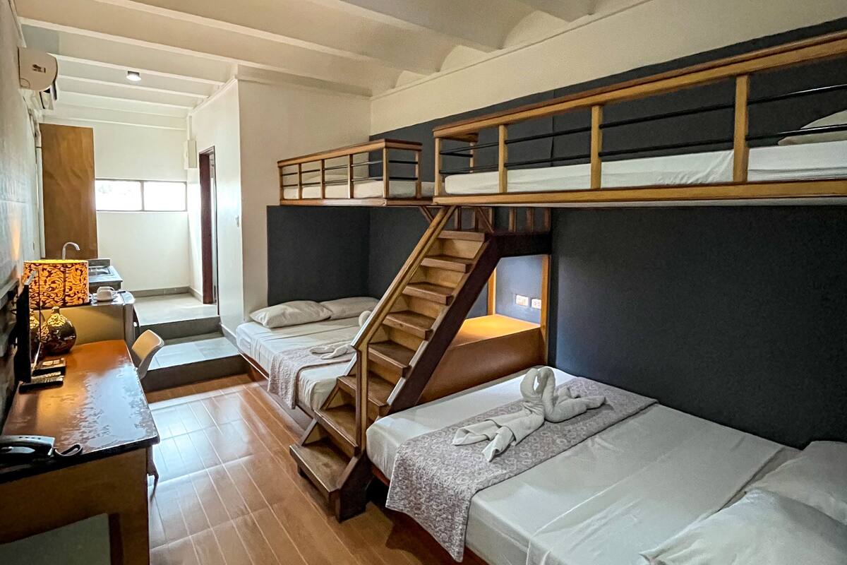 Une chambre de dortoir avec des lits superposés, un bureau avec une lampe et un escalier.