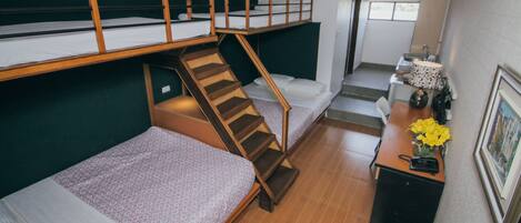 Un dormitorio con literas, un escritorio, una silla y una escalera.