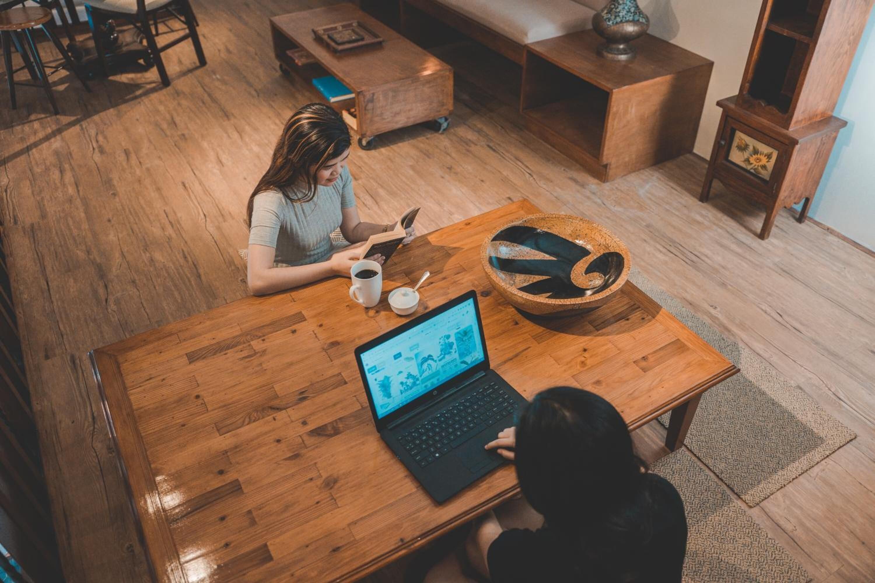 A wooden table with a laptop, a cup, and a bowl.