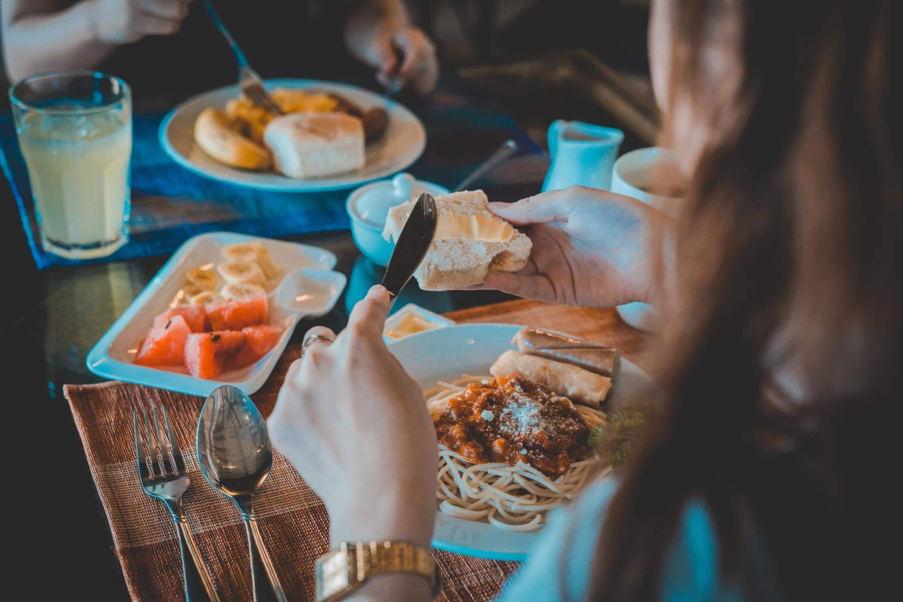 Una mesa de comedor con platos de comida, cubiertos y un vaso de bebida.
