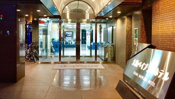The entrance of the Osaka Bay Plaza Hotel with a modern design, glass doors, and a signboard. - Osaka Bay Plaza Hotel (Sakai)