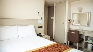 A hotel room with a bed, bedside table, phone, mirror, and a desk with a chair. - Osaka Bay Plaza Hotel (Sakai)