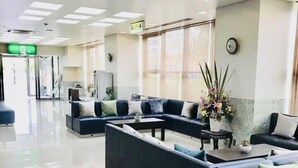 A modern waiting area with dark blue sofas, a tiled floor, and a large window with curtains. - Osaka Bay Plaza Hotel (Sakai)
