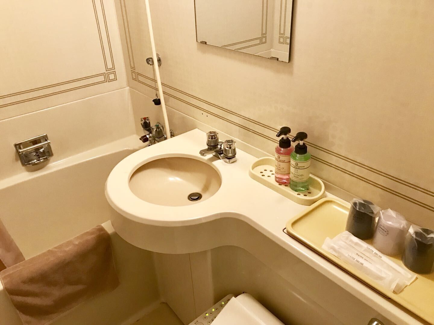 A bathroom with a sink, mirror, towel rack, and toiletries.