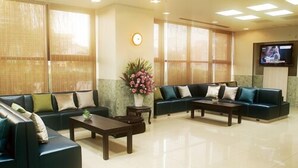 A spacious lobby with two sofas, a coffee table, and a TV screen. - Osaka Bay Plaza Hotel (Sakai)