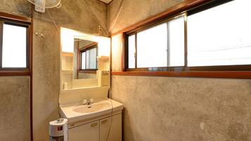 A bathroom with a large mirror, a sink, a toilet, a fan, and a window.