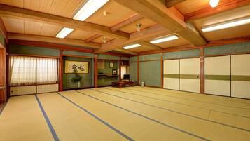 A traditional Japanese room with tatami flooring, sliding doors, and a ceiling with wooden beams and skylights.