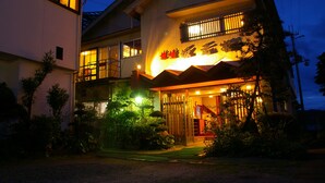 Un bâtiment à deux étages de style architectural traditionnel, doté d’une entrée imposante avec un porche abrité et d’un escalier bien visible menant à l’étage supérieur.