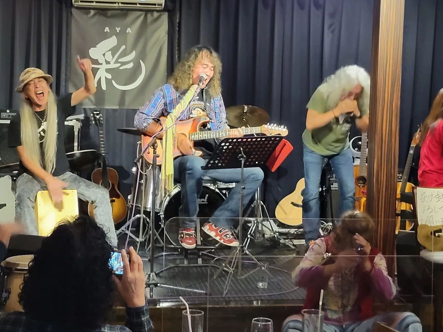 A band performing on a stage with musical instruments and a drum set.