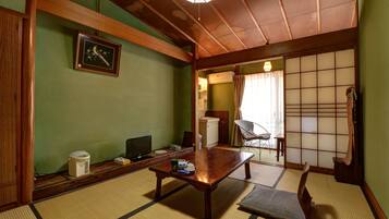 Una habitación japonesa tradicional con suelo de tatami, una mesa de madera baja, un televisor y un futón.