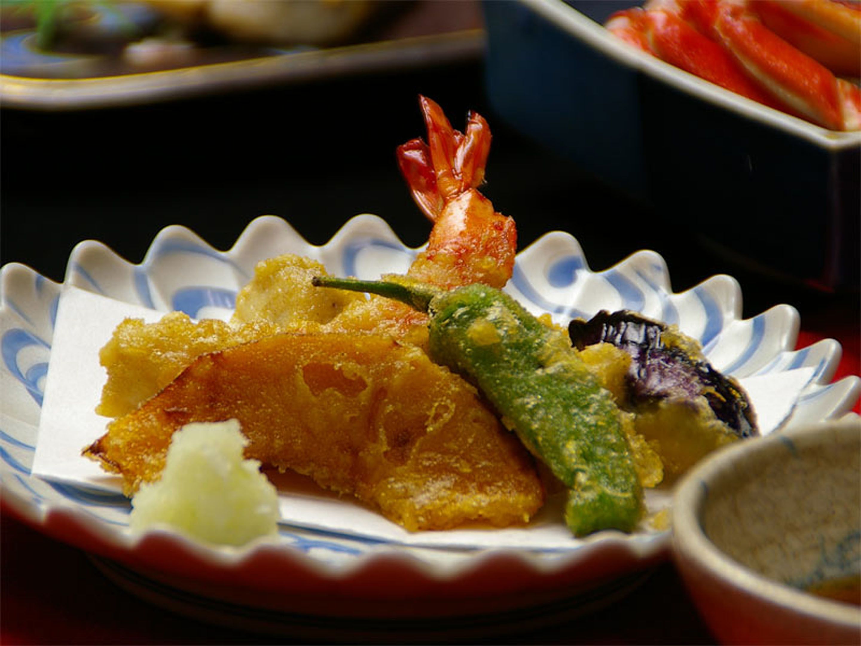 A plate with tempura shrimp, vegetables, and a small bowl of dipping sauce.