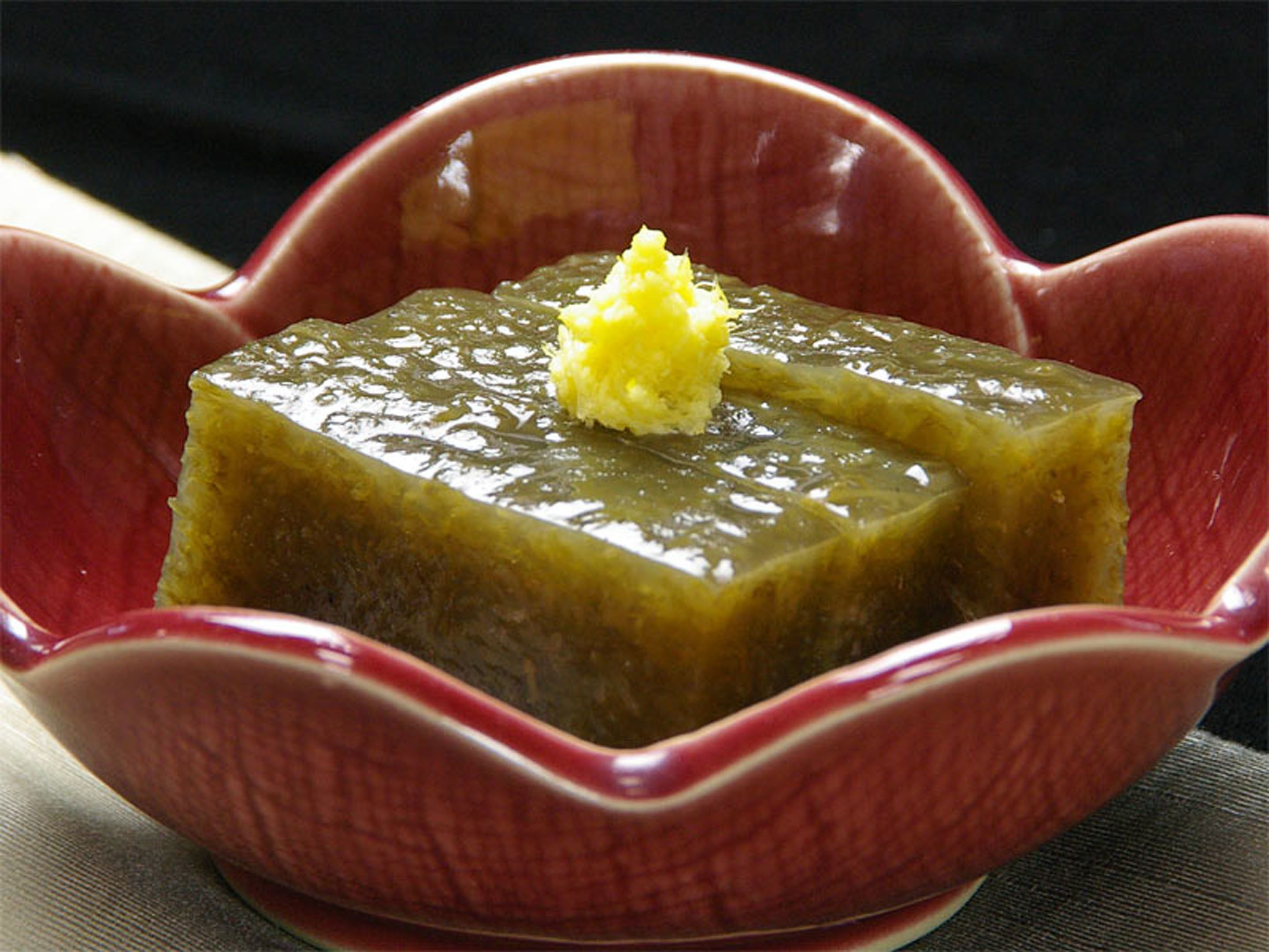 A square-shaped dessert in a red, scalloped bowl.