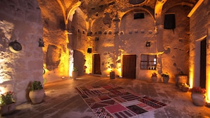 A historic interior with stone walls, wooden doors, and a patterned rug on the floor. - Tulip Cave Suites (Nevsehir)