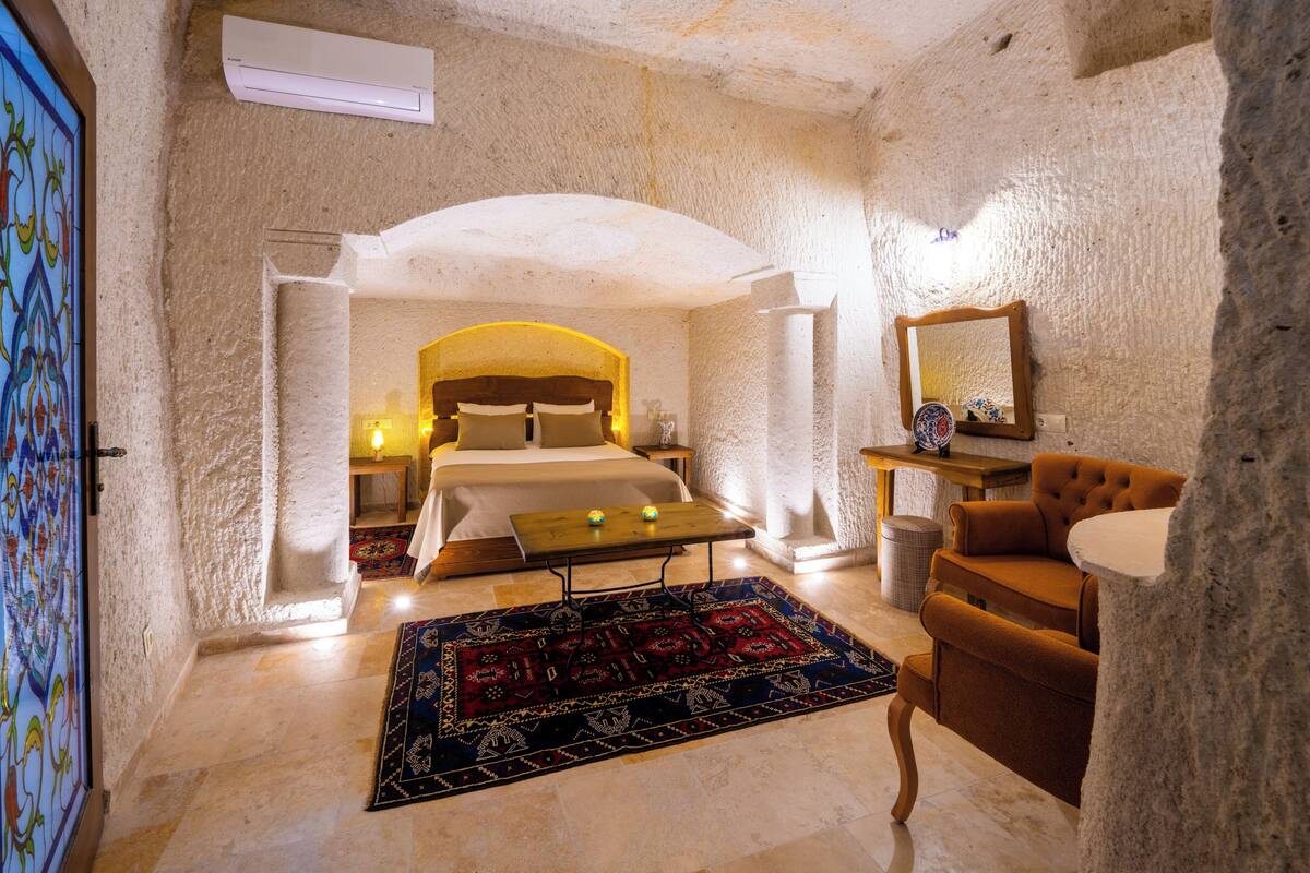 Una habitación con cama, una mesita, una silla, un espejo y una alfombra.