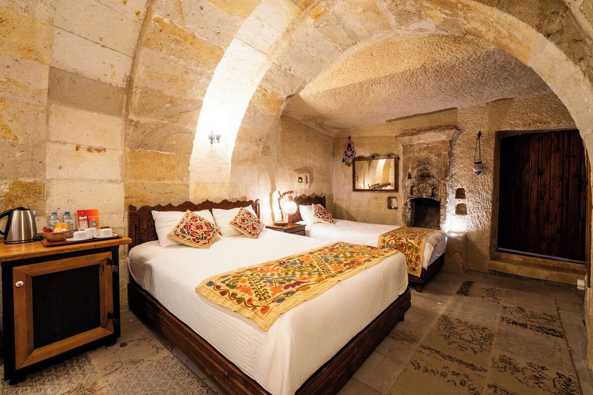 Una habitación con una cama, un armario de madera, un espejo y una pared de piedra.