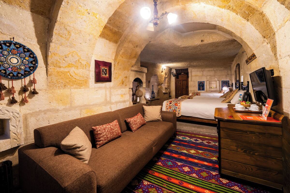 Una habitación con sofá, cama, cómoda de madera y alfombra colorida.