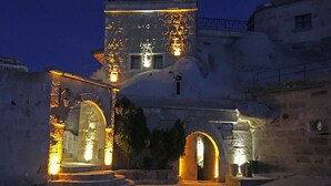 A historic building with illuminated arches and a stone staircase leading to the entrance. - Tulip Cave Suites (Nevsehir)