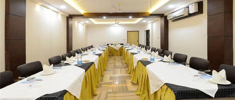 Uma sala de conferências com mesas compridas, cadeiras e toalha de mesa amarela.