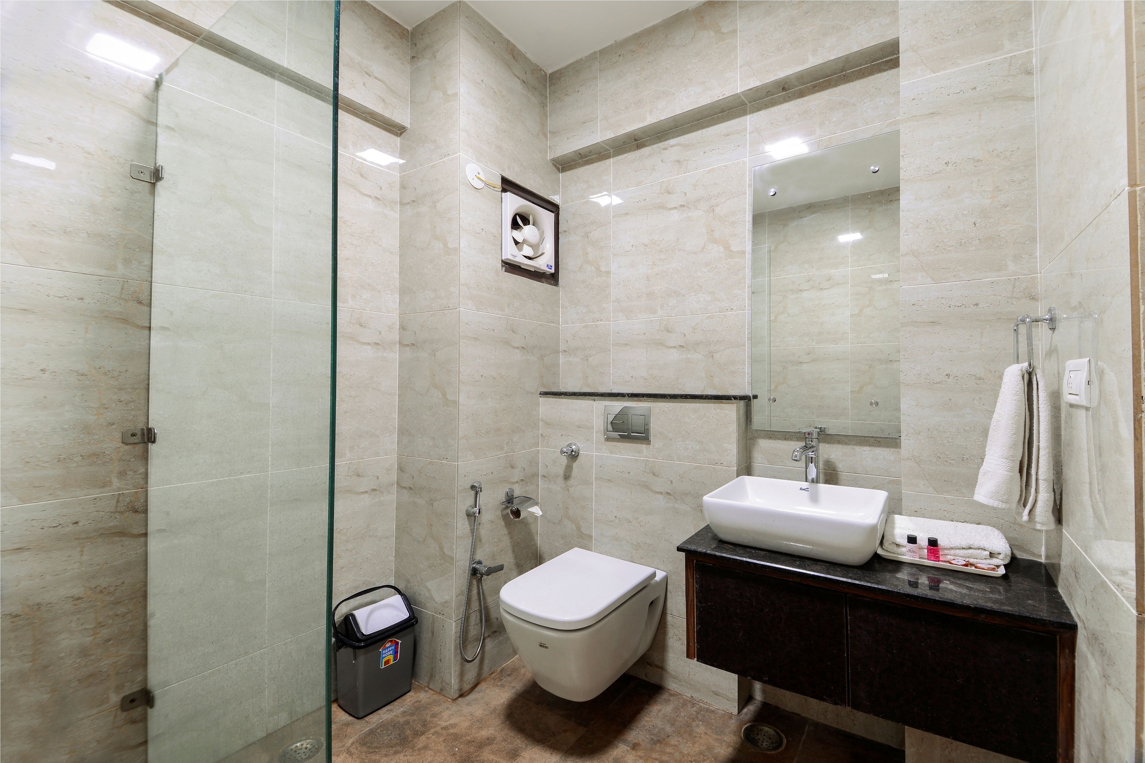 A modern bathroom with a glass shower enclosure, a white toilet, a sink, and a mirror.