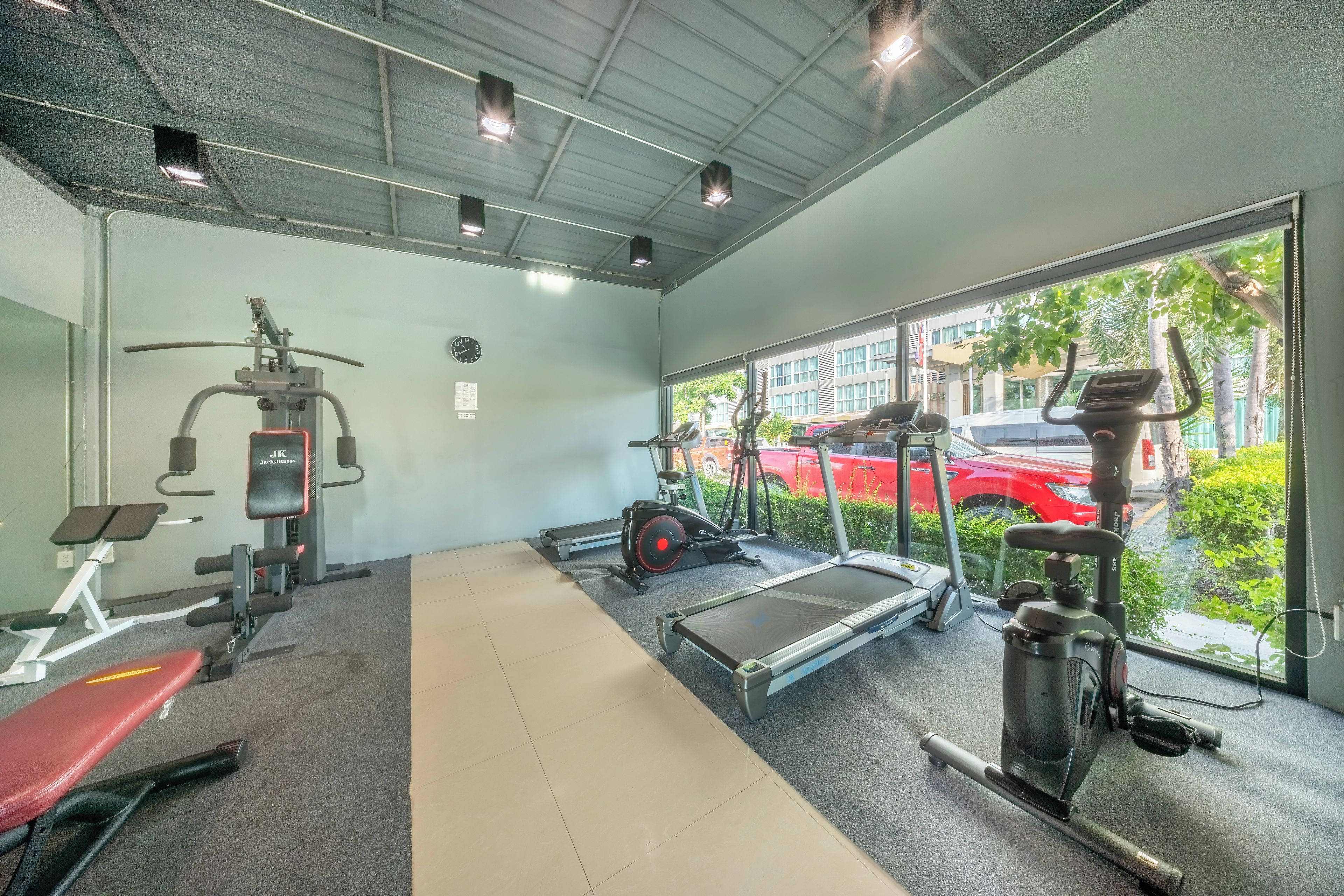 A gym with exercise equipment, a treadmill, and a large window offering a view of the outside.