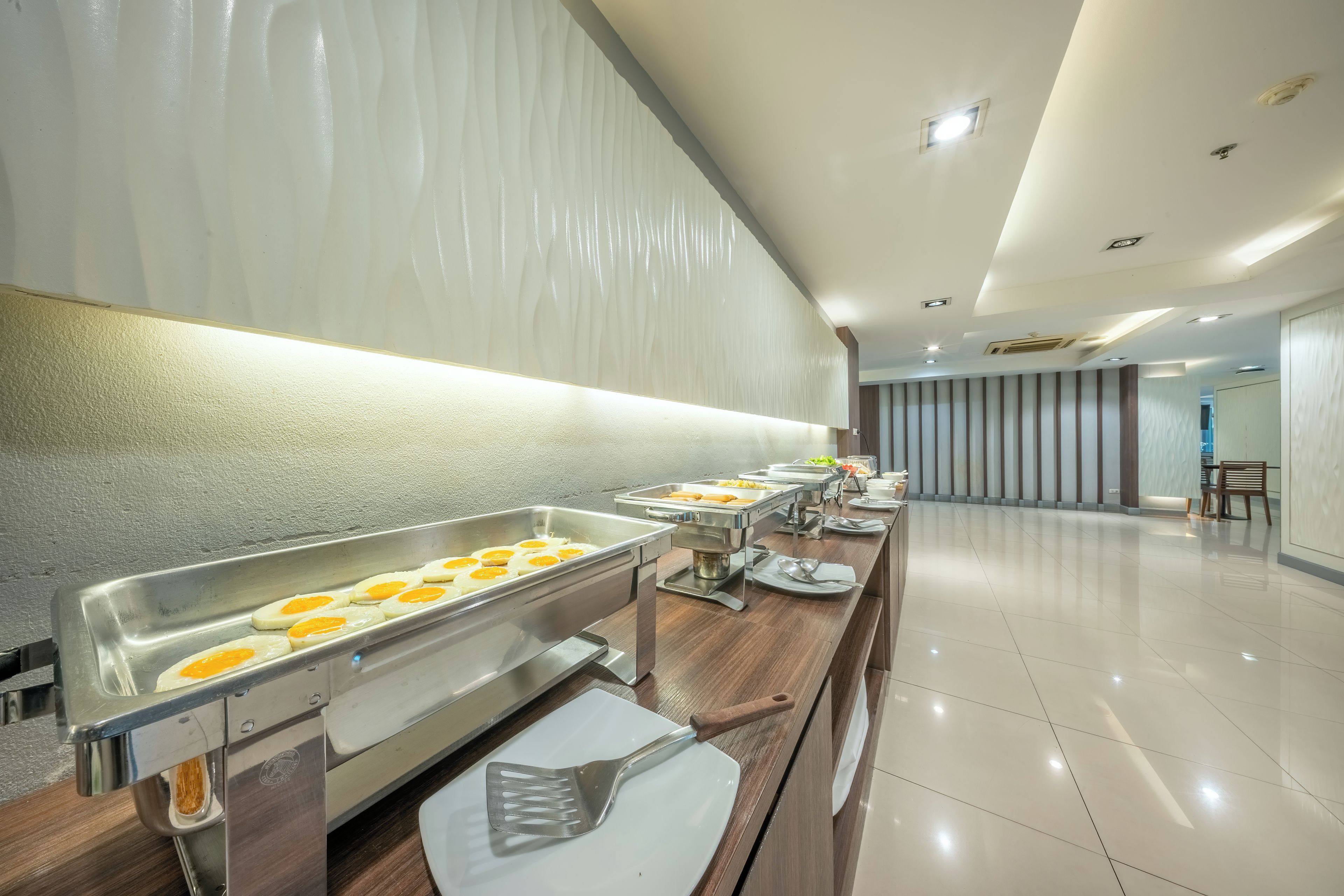 Montaje tipo bufé con múltiples estaciones de comida, piso pulido y diseño interior moderno.