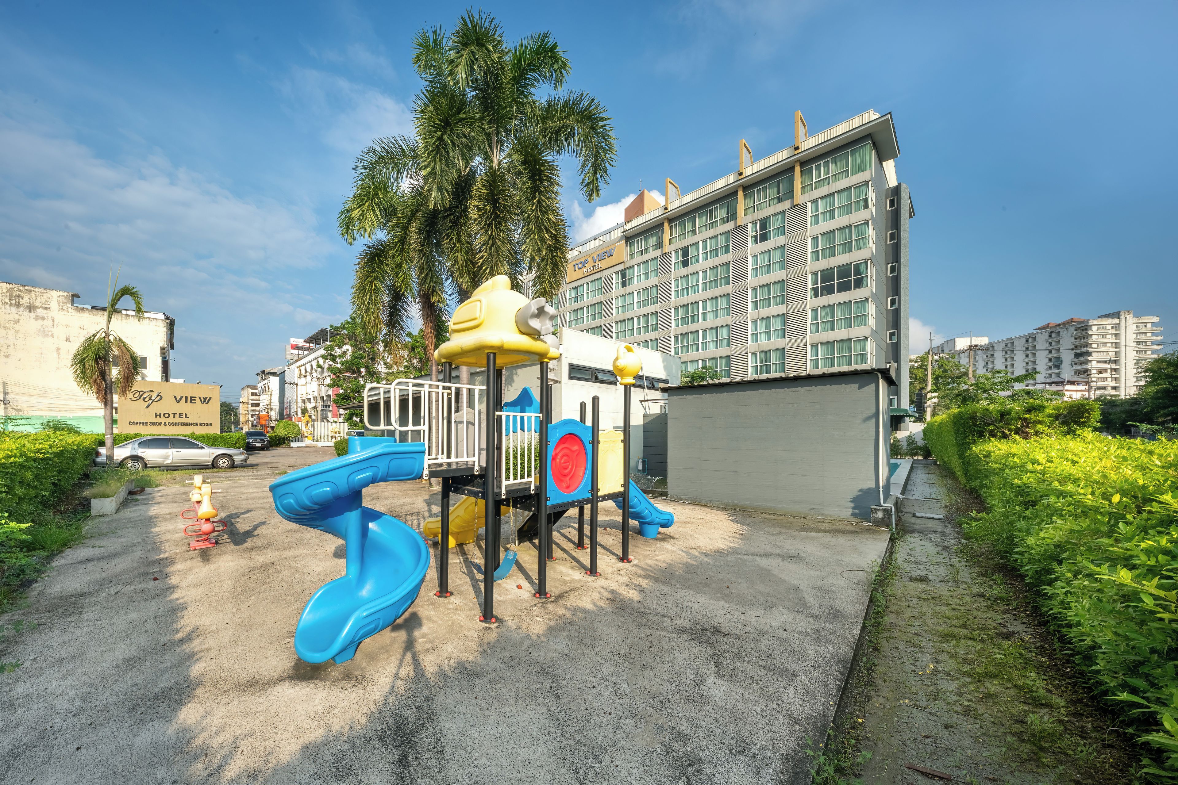 A playground with slides and climbing structures, surrounded by a building with a sign that reads 'View Hotel'.