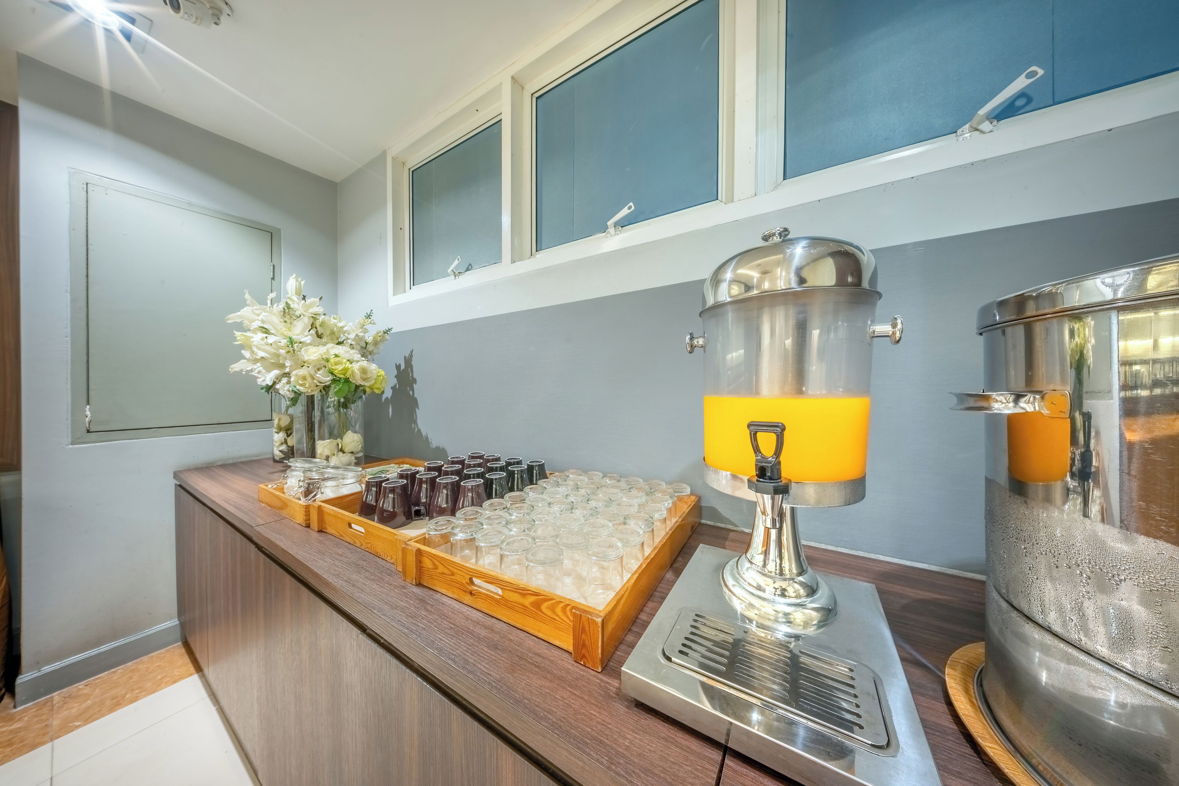 A kitchen area with a coffee machine, a fruit dispenser, and various containers for food and drinks.