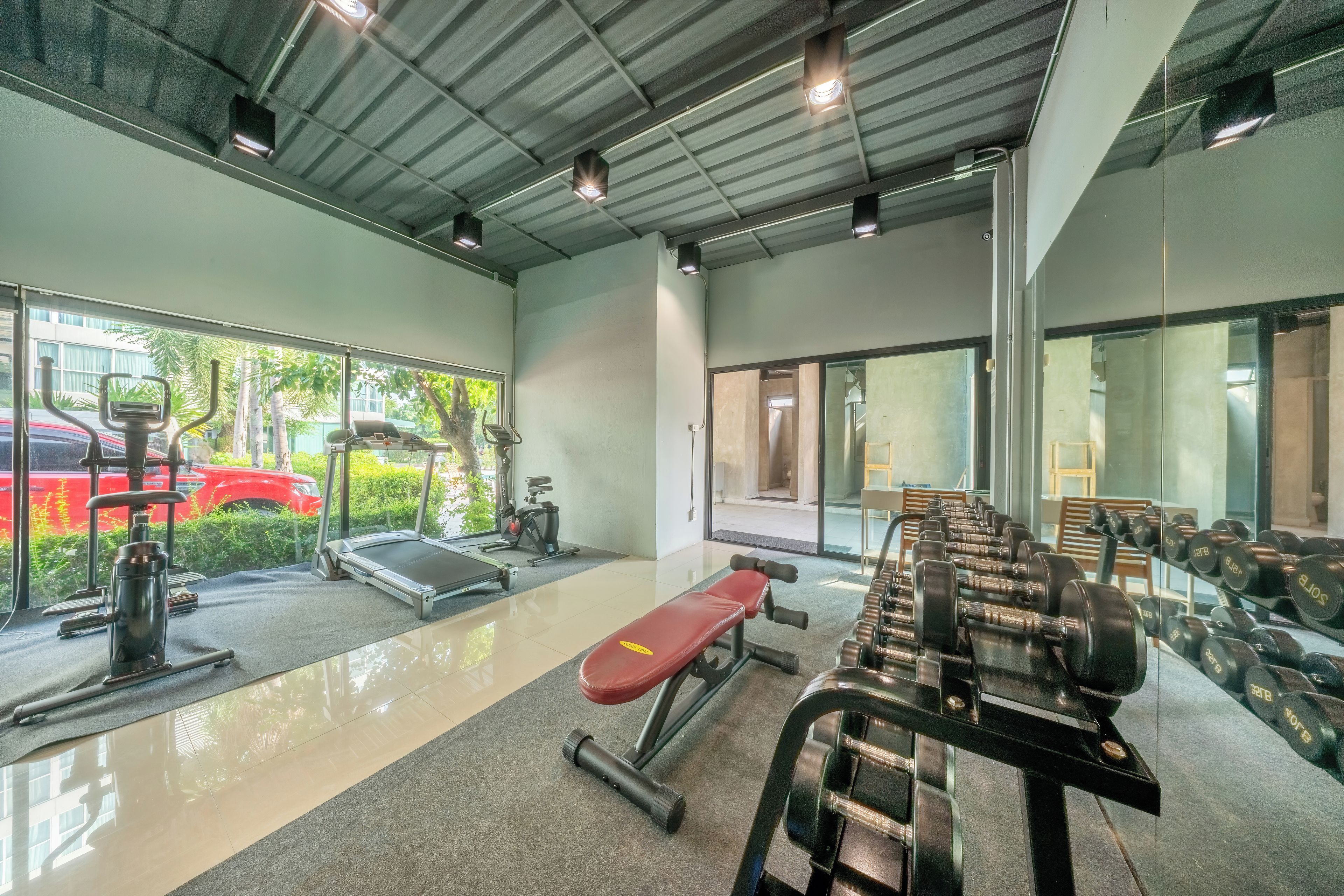 Un gimnasio con equipo de ejercicio, cinta de correr y banco.