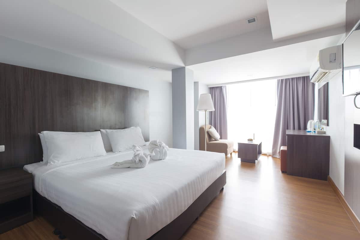 A modern hotel room with a large bed, a desk, and a chair.