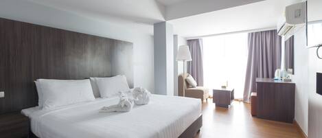 A modern hotel room with a large bed, a desk, and a chair.