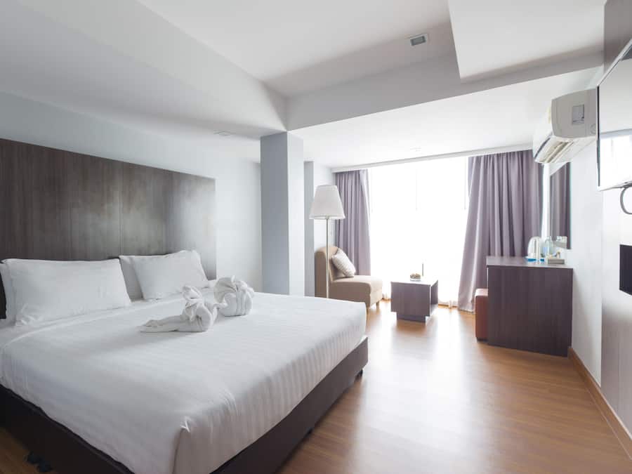 A modern hotel room with a large bed, a desk, and a chair.