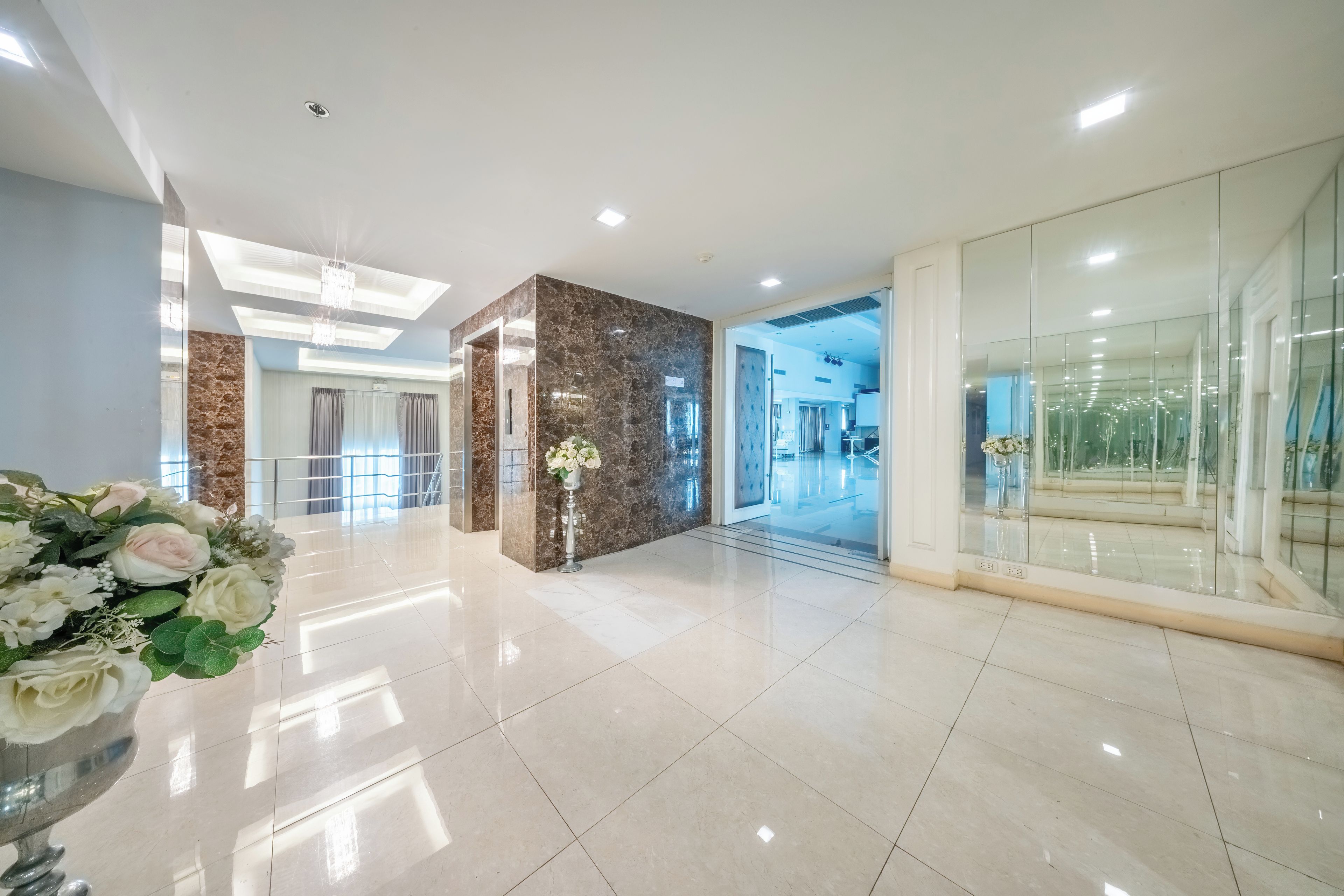 A modern hotel lobby with a marble reception desk, a glass partition, and a chandelier.
