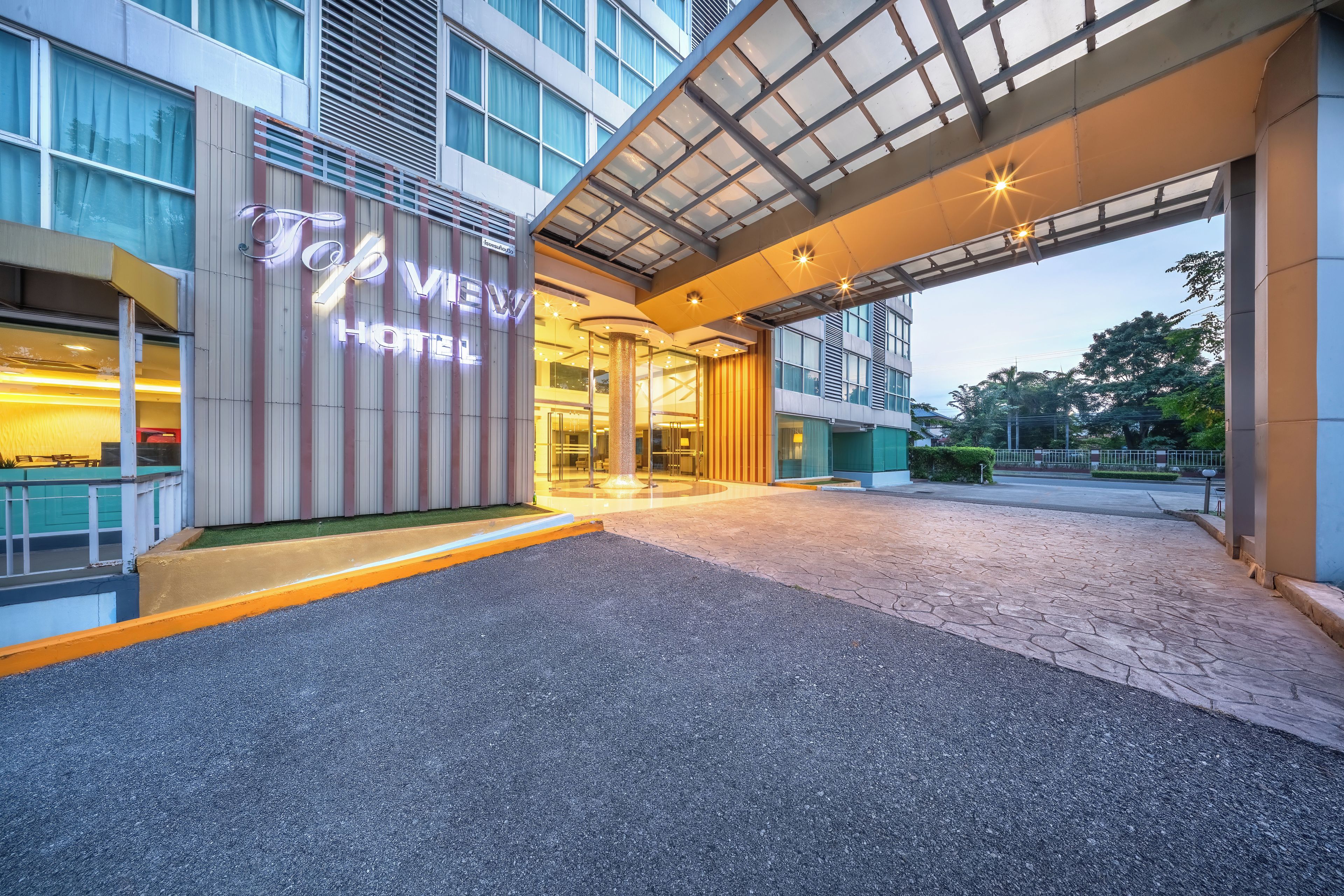 Entrada de hotel con diseño moderno, que presenta fachada de vidrio y un área de acceso bien iluminada.