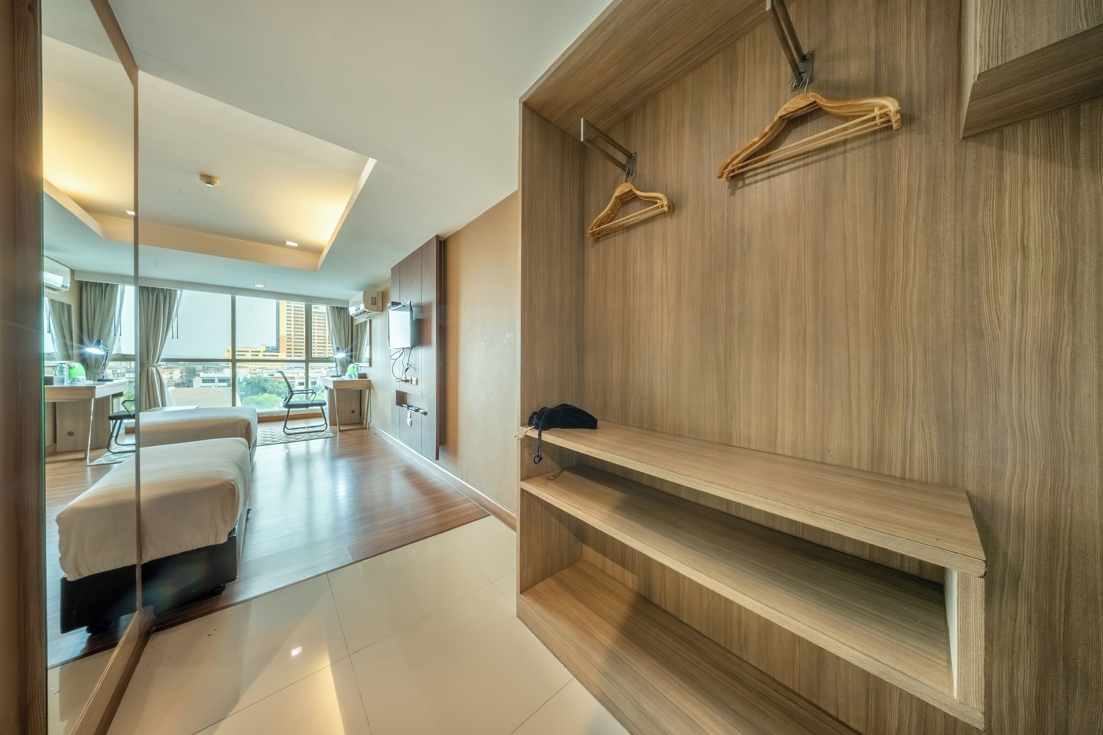 Una habitación de hotel moderna con una cama grande, un escritorio y un armario con perchas de madera.