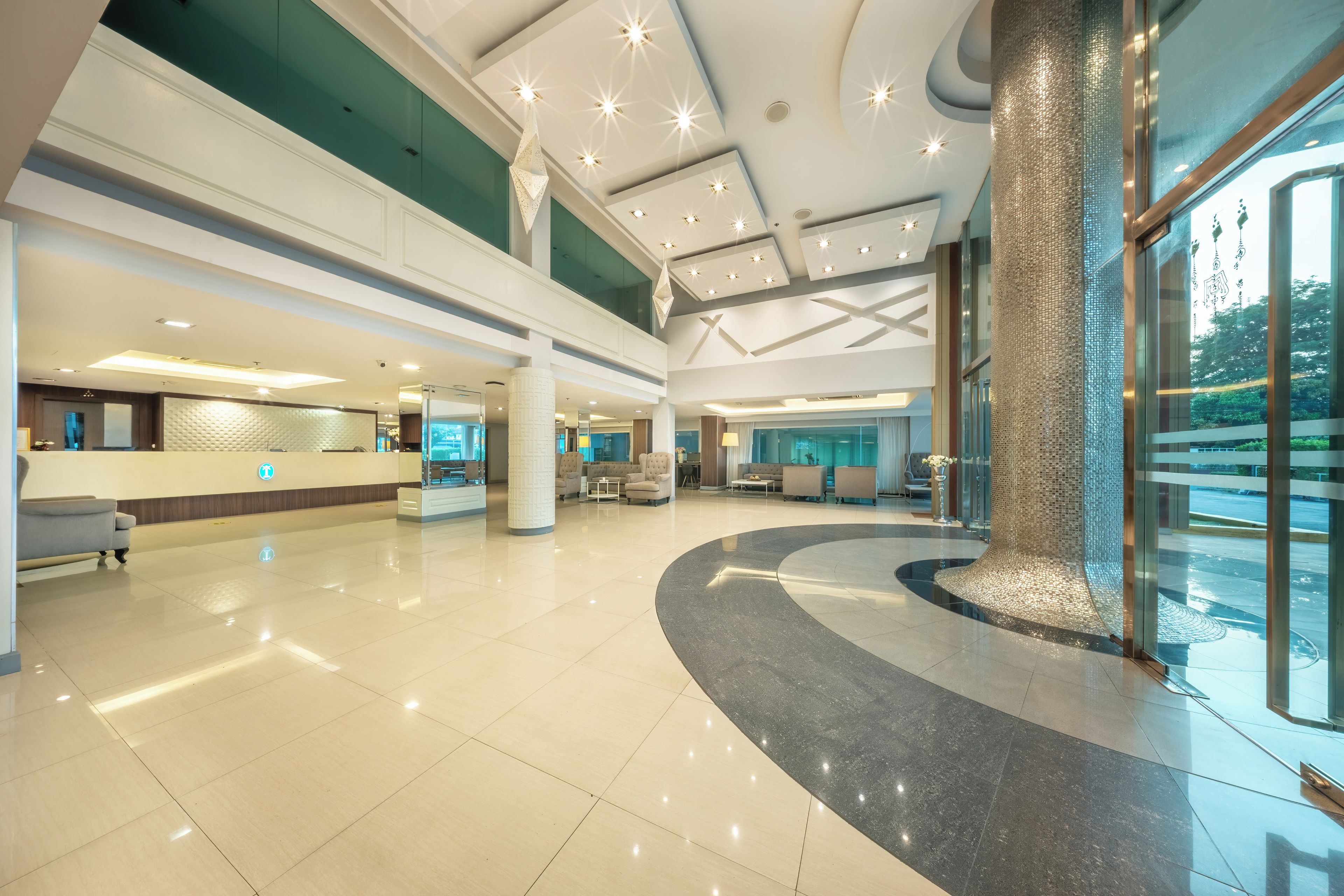 A spacious lobby with a reception desk, seating area, and a large pillar.