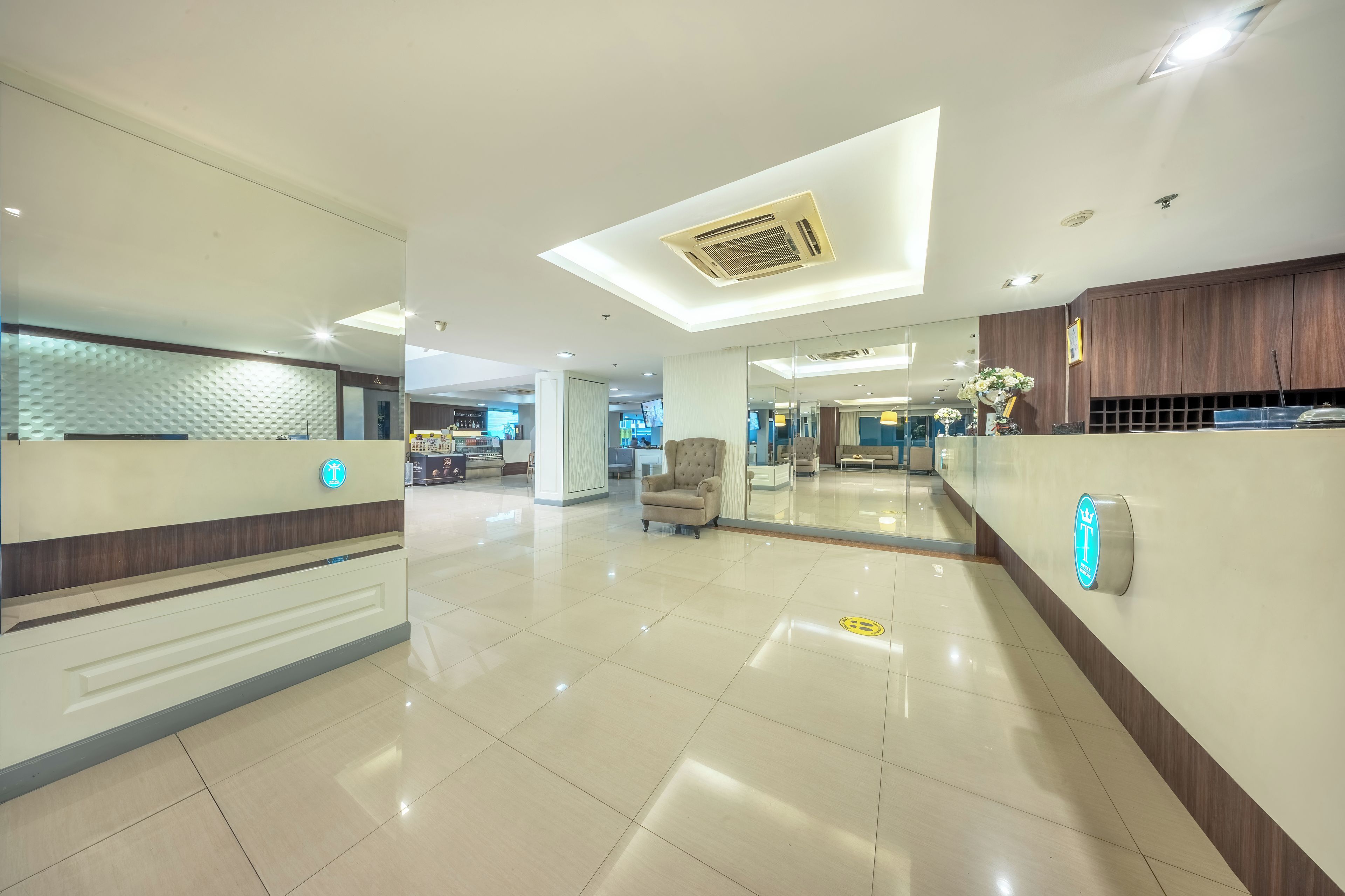 Un hall de hotel con una recepción, área de descanso y un diseño de techo moderno.