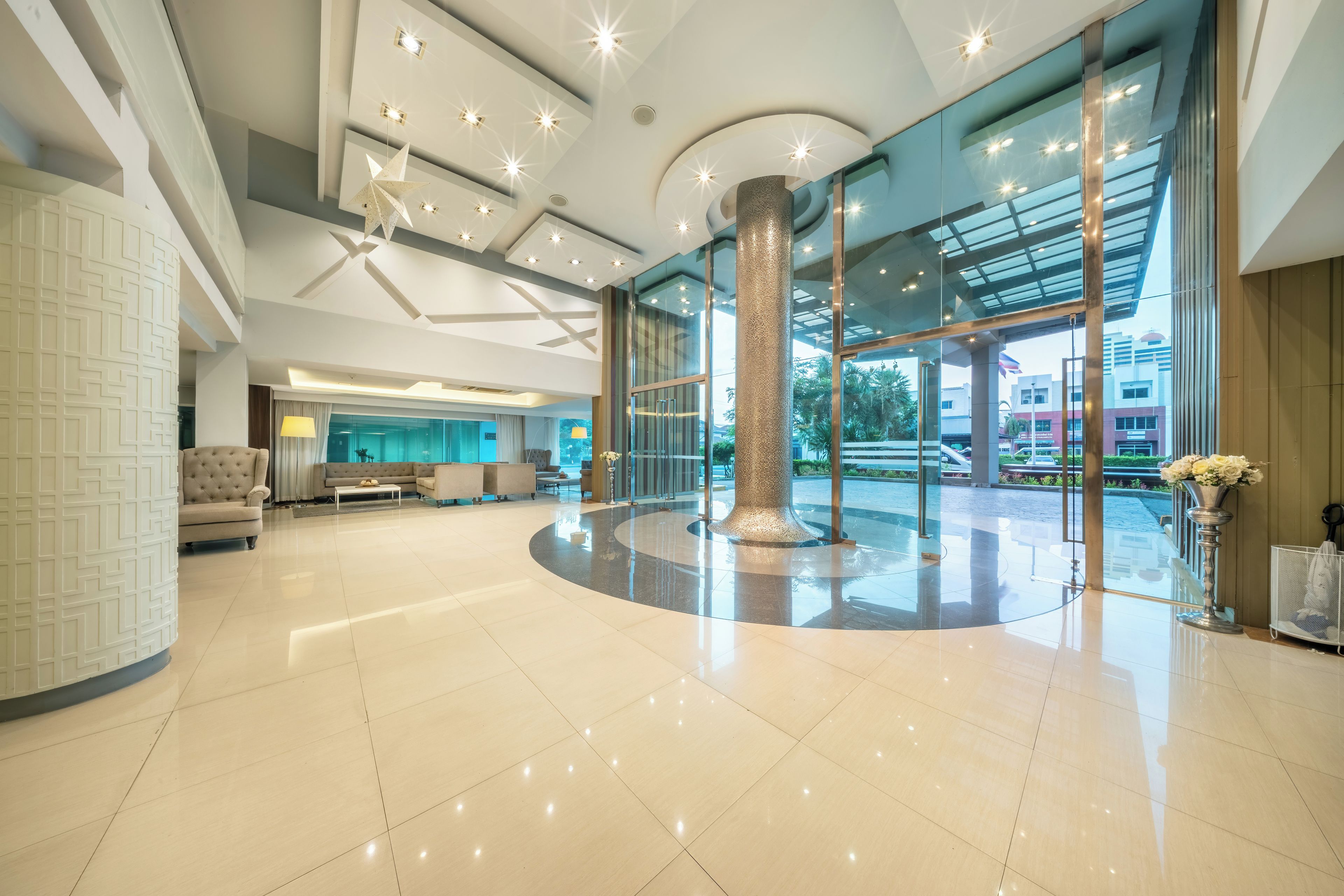 A spacious lobby with a central column, seating area, and large windows offering views of the outside.
