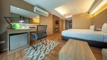 Una habitación de hotel con escritorio, silla, cama y una pequeña kitchenette.