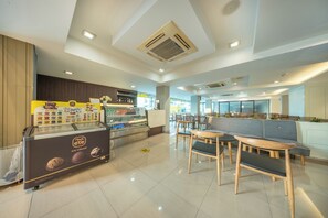 A modern cafe interior with a self-service ice cream machine, seating area, and a view of the street outside.