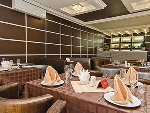 Un restaurant où les tables sont dressées pour le service, avec des nappes à carreaux et des serviettes soigneusement pliées.