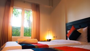 A hotel room with two beds, a nightstand with a lamp, and a window with curtains. - Pova Residence and Boutiques Resort (Chonburi)