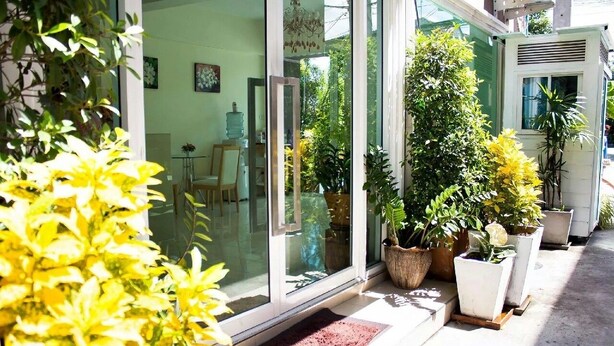 A modern building with large glass doors, potted plants, and a visible interior with furniture. - Pova Residence and Boutiques Resort (Chonburi)