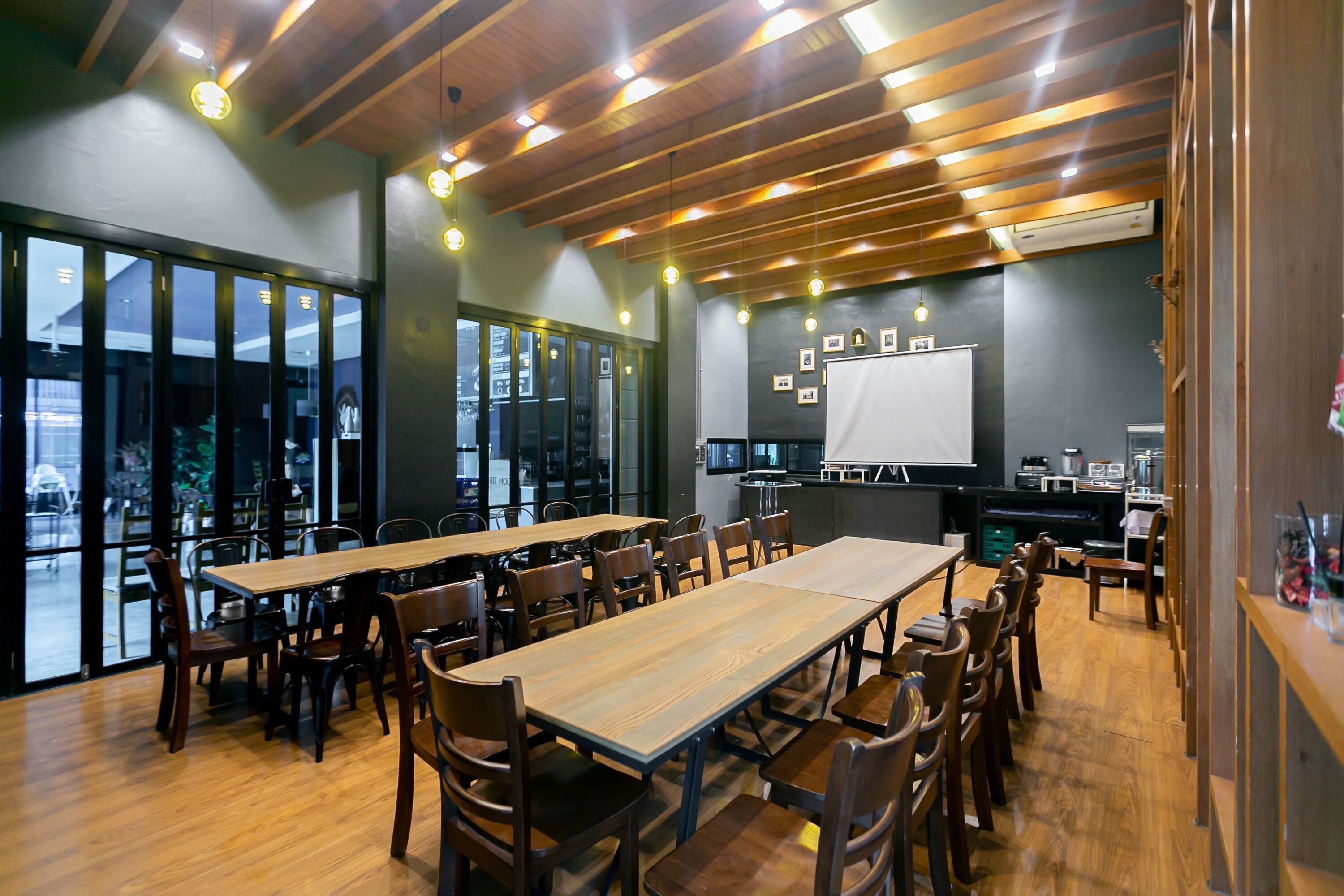 A conference room with wooden tables and chairs, large windows, and a whiteboard.