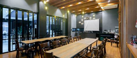 A conference room with wooden tables and chairs, large windows, and a whiteboard.