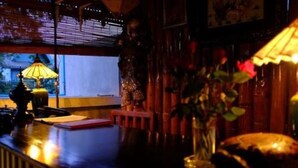 A dimly lit room with a wooden desk, a lamp, and a vase with flowers.