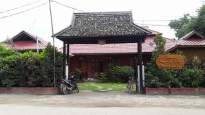A traditional wooden building with a tiled roof, a covered entrance, and a sign indicating it is a guest house.