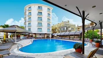 Een buitenzwembad, parasols bij het zwembad en ligstoelen