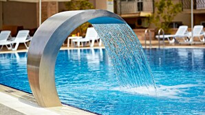 A pool with a modern water feature, surrounded by lounge chairs and umbrellas. - Ayvalik Cinar Hotel (Ayvalik)