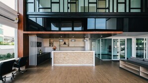 A modern reception area with a wooden reception desk, black office chairs, and a glass partition. - MT Park Residence (Chonburi)