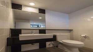 A modern bathroom with a white sink, black countertop, and a white toilet. - MT Park Residence (Chonburi)
